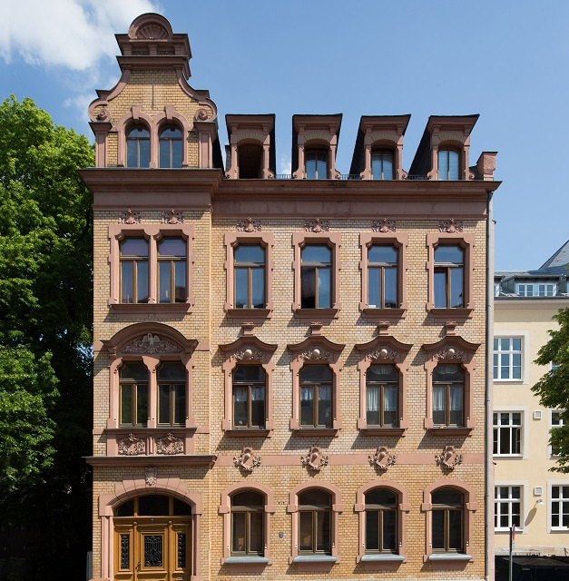 Viergeschossiges Wohn- und Geschäftshaus mit reich verzierter Sandsteinfassade, hohen Fenstern und ausgebautem Dachgeschoss mit Gauben.