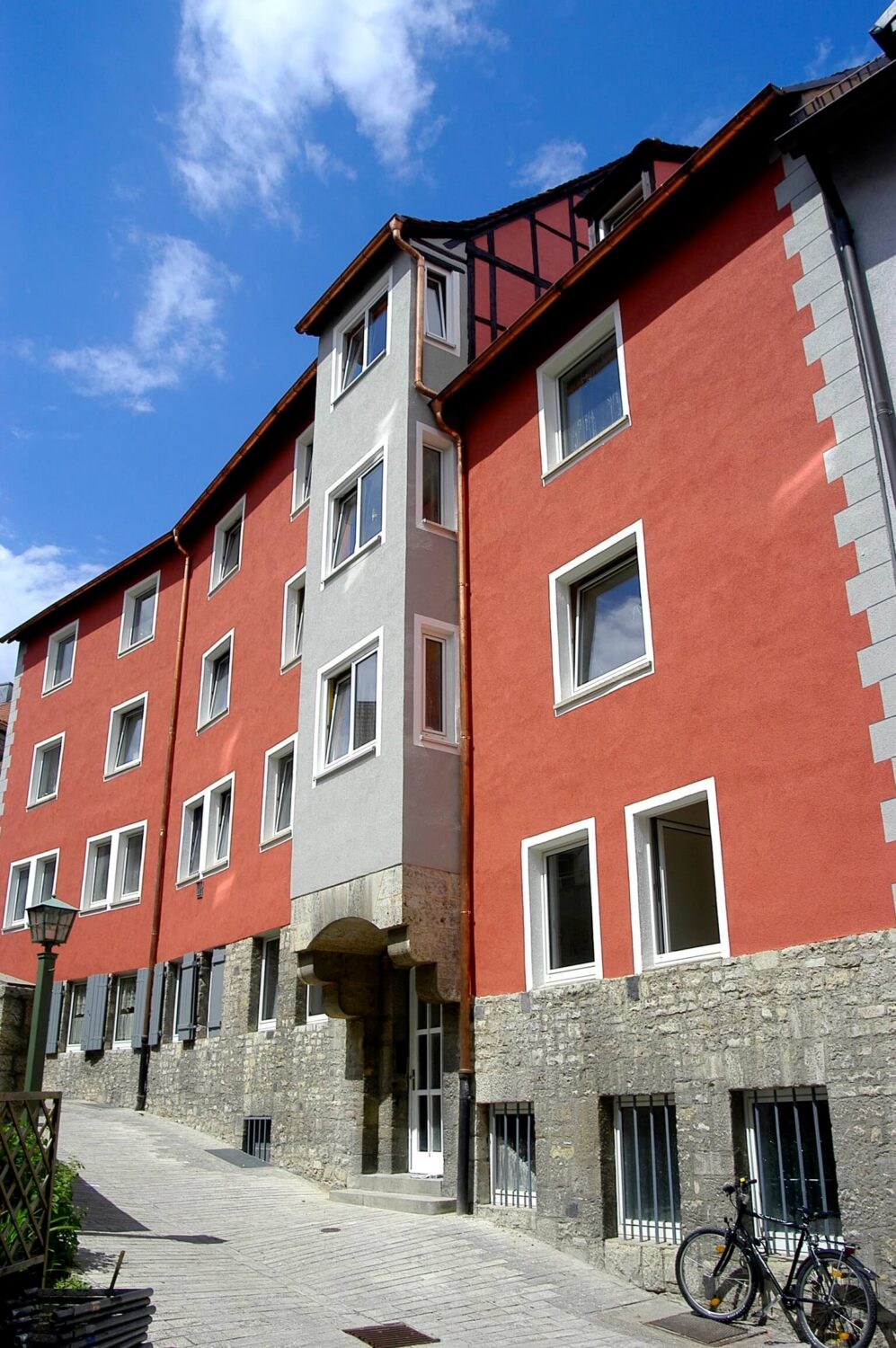 Dreigeschossiges Wohngebäude mit orangener Fassade und ausgebautem Dachgeschoss